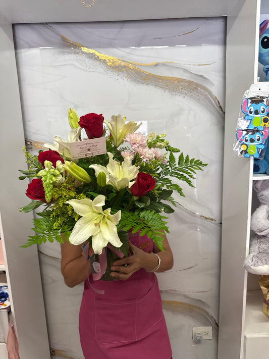 Jarrón con rosas rojas, lirios y follaje premium